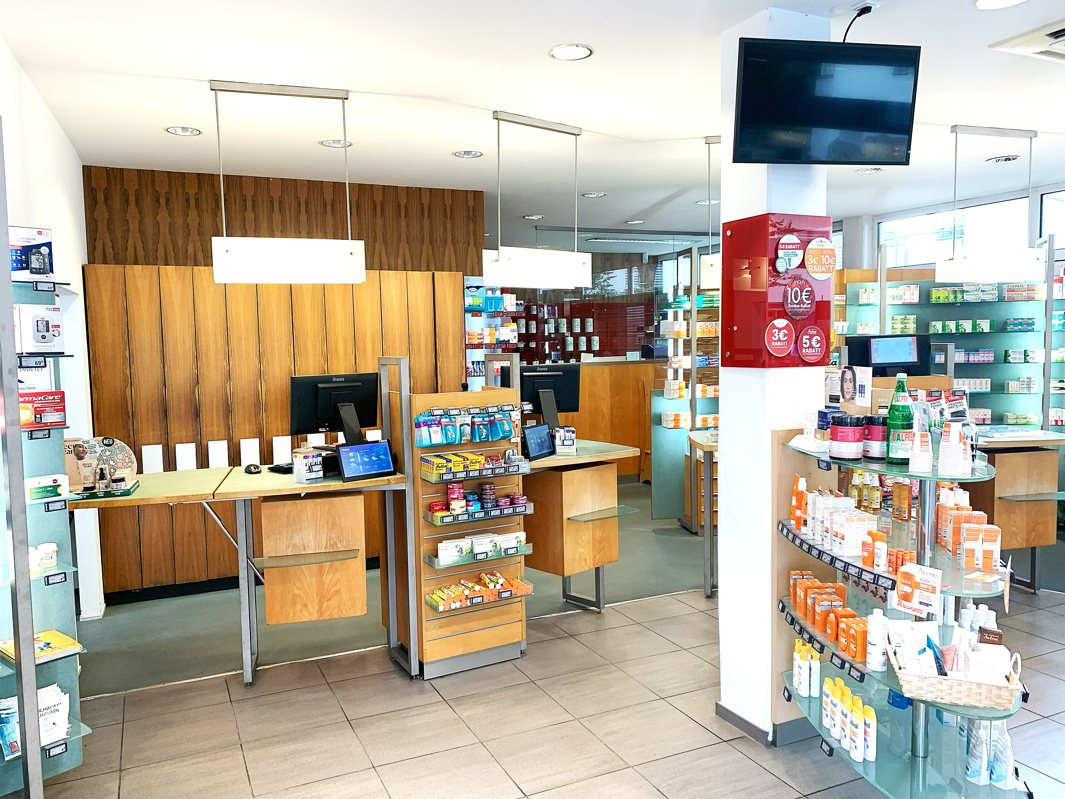 Verkaufstresen der Burg-Apotheke in Hennef mit Regalen voller Apotheken- und Pflegeprodukte sowie moderner Kassentechnik.